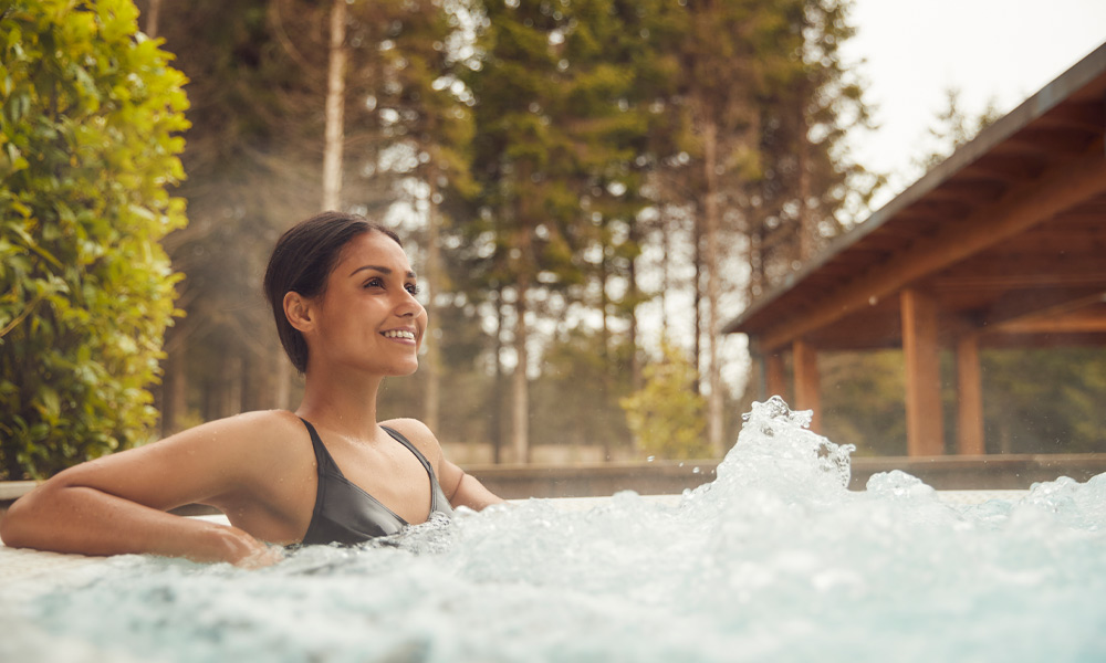 Woman soaking in a bubbling outdoor hot tub.