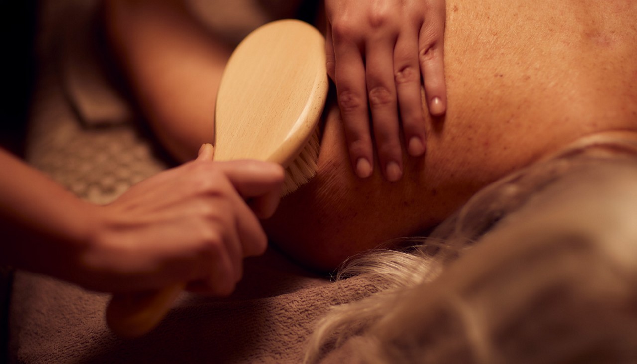 Soft bristle brush being stroked against a ladies shoulder. 