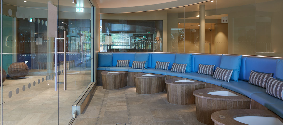 curved seat in front of foot baths with glass door to area