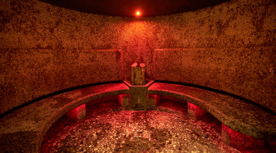 Curved stone seating in the glowing Volcanic Steam room.