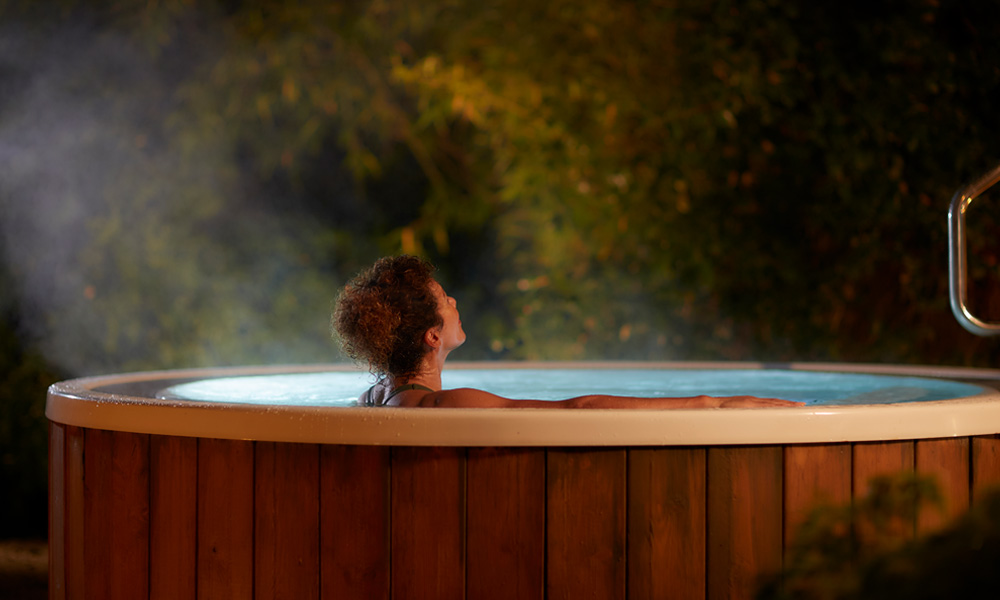 Woman soaking in an outdoor bubbling hot tub.