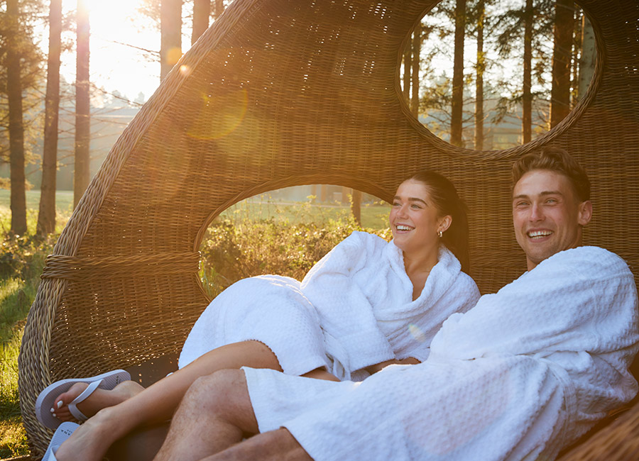 Couple sitting in a cosy seat surrounded by the forest.