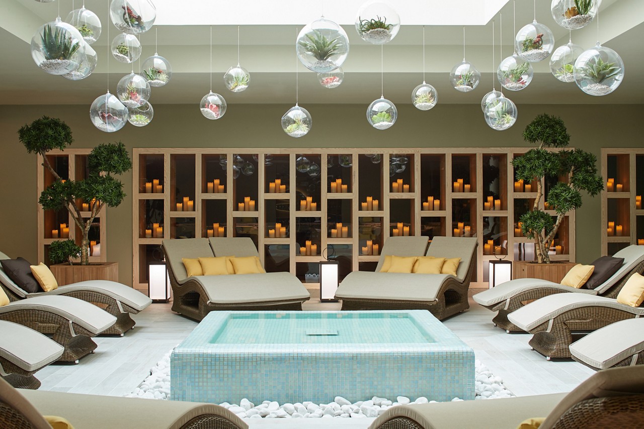 Cushioned lounging beds surrounding a tiled water feature inside the Forest Garden.