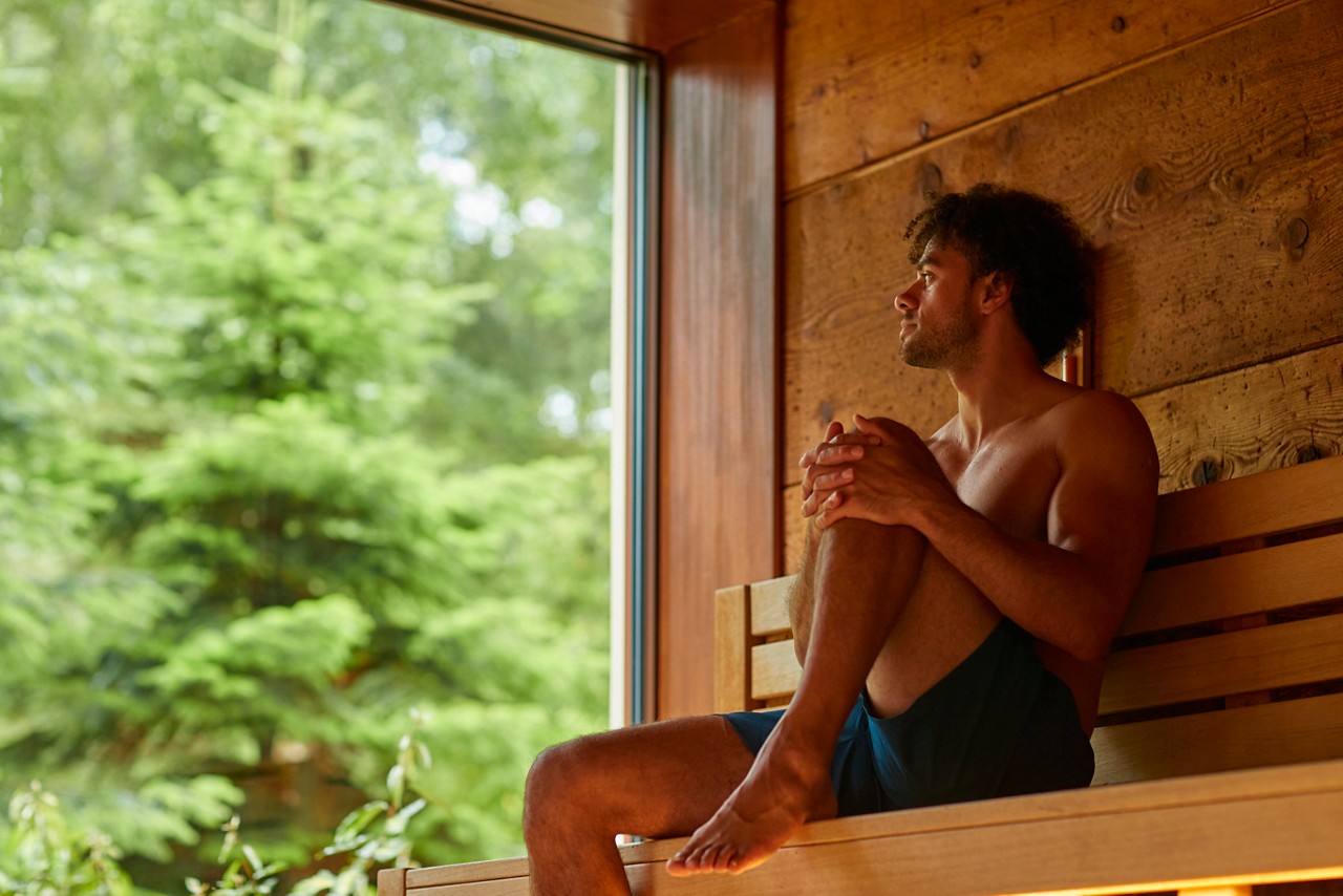 Man enjoying the forest views from inside the Nordic Sauna.