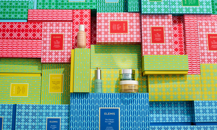 Colourful Elemis gift boxes with Elemis products displayed.