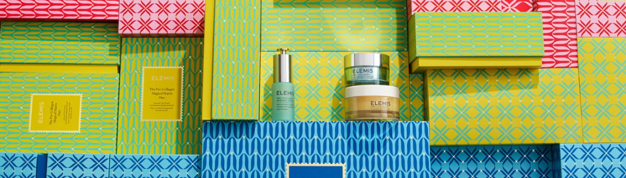 Colourful Elemis gift boxes with Elemis products displayed.