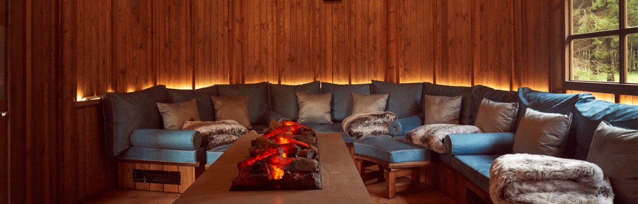 nordic snug with log fire and sofa with blankets and pillows