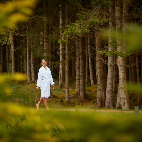 Woman walking in a bath robe by woodlands