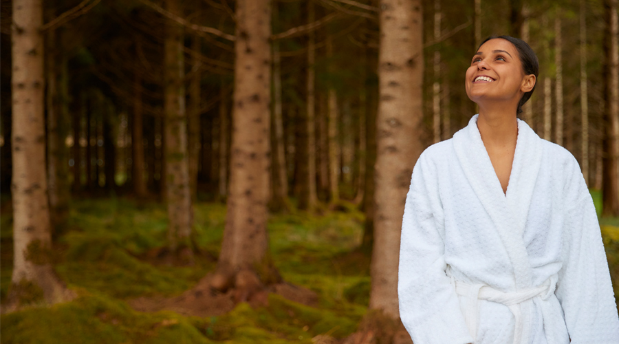 Woman walking through the forest in a fluffy spa robe.