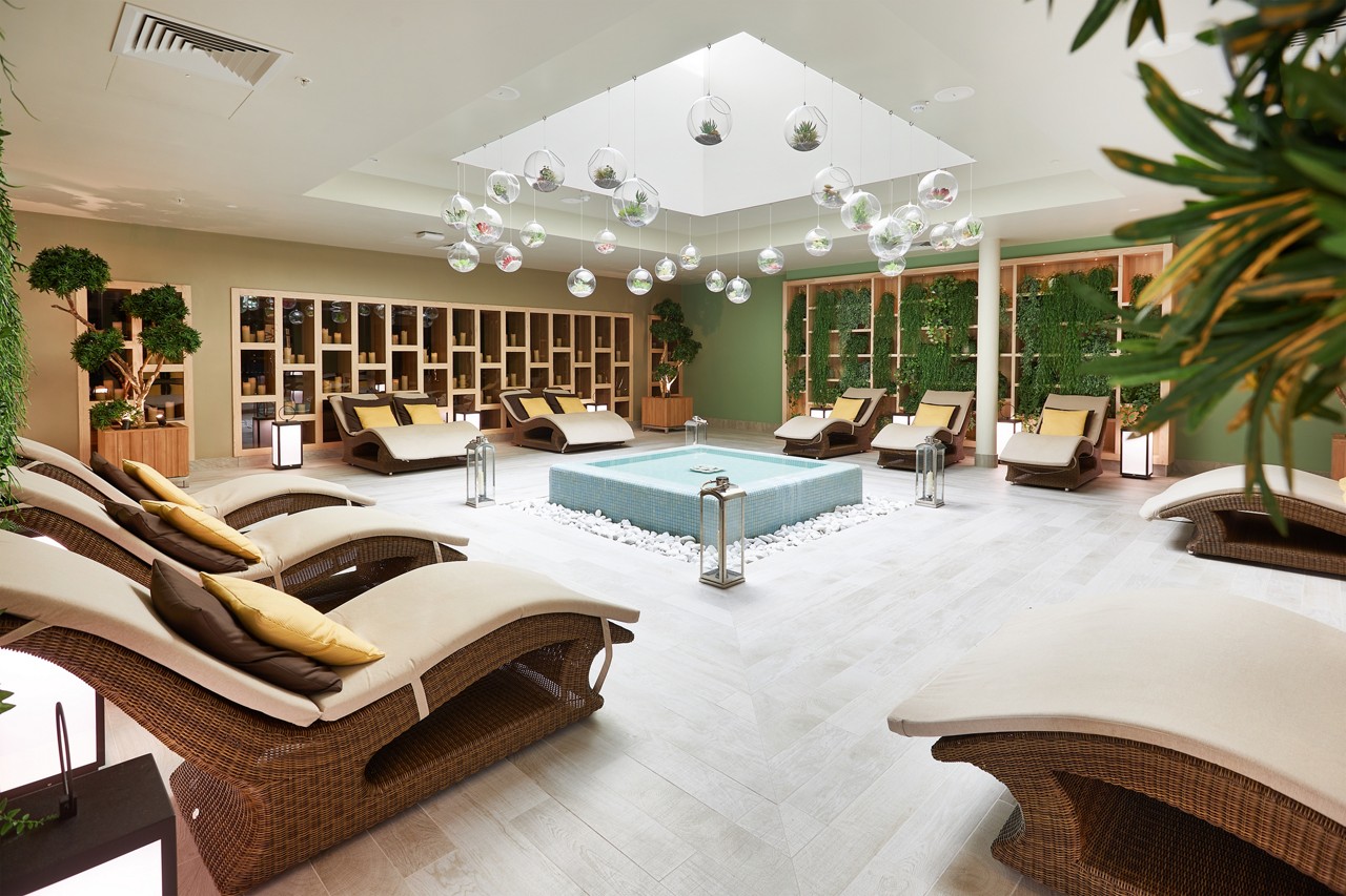 Cushioned lounging beds surrounding a tiled water feature inside the Forest Garden.