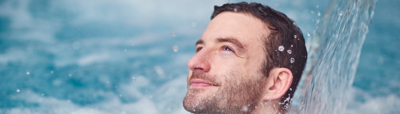 man in pool under water feature