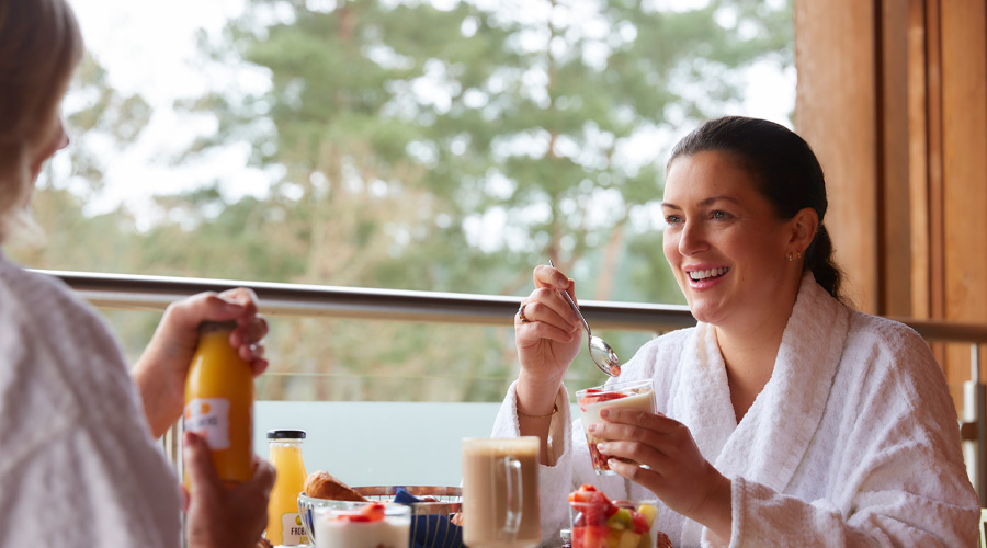 Two woman sitting having breakfast on their Spa Suite balcony.