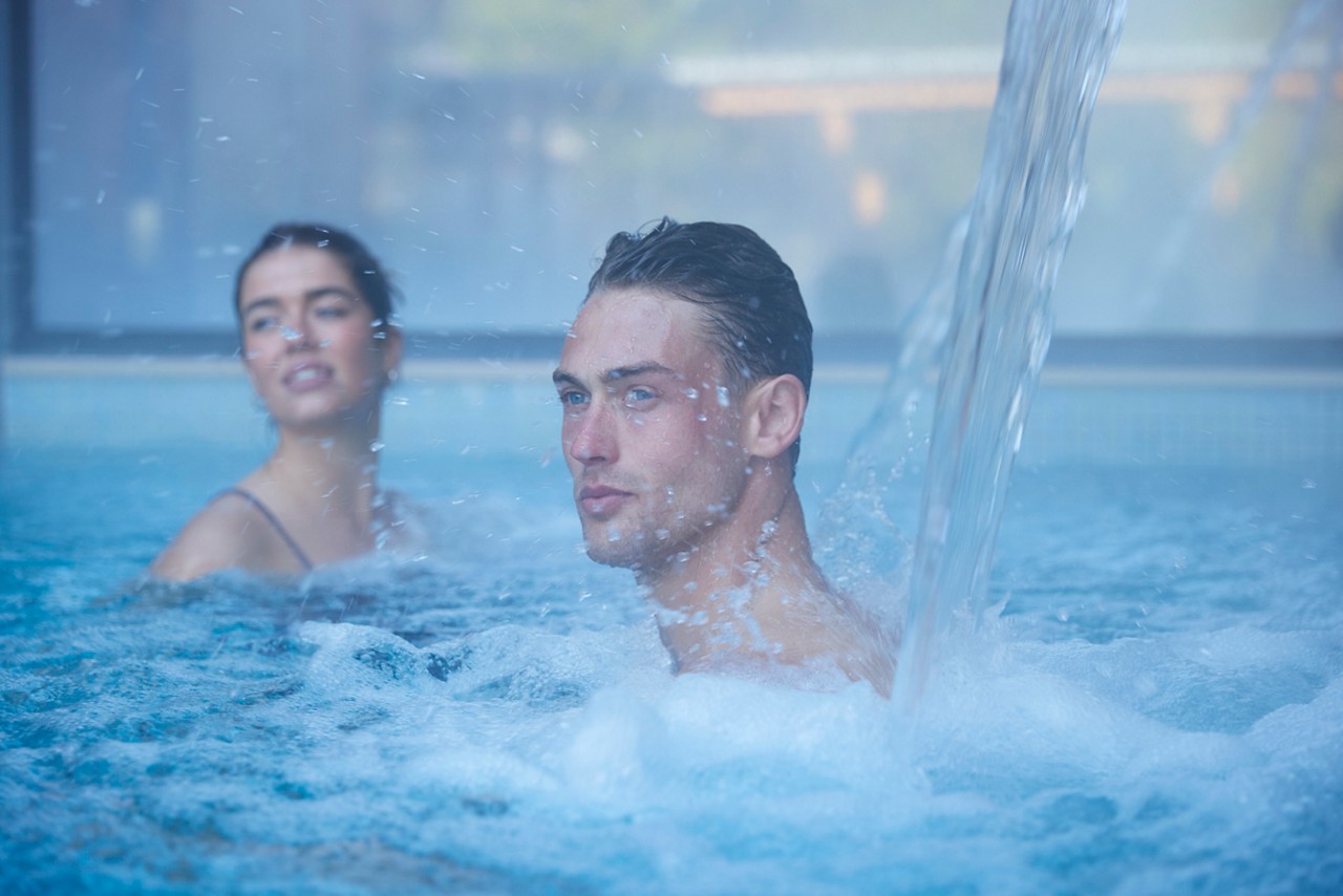 man under the water jet in the pool