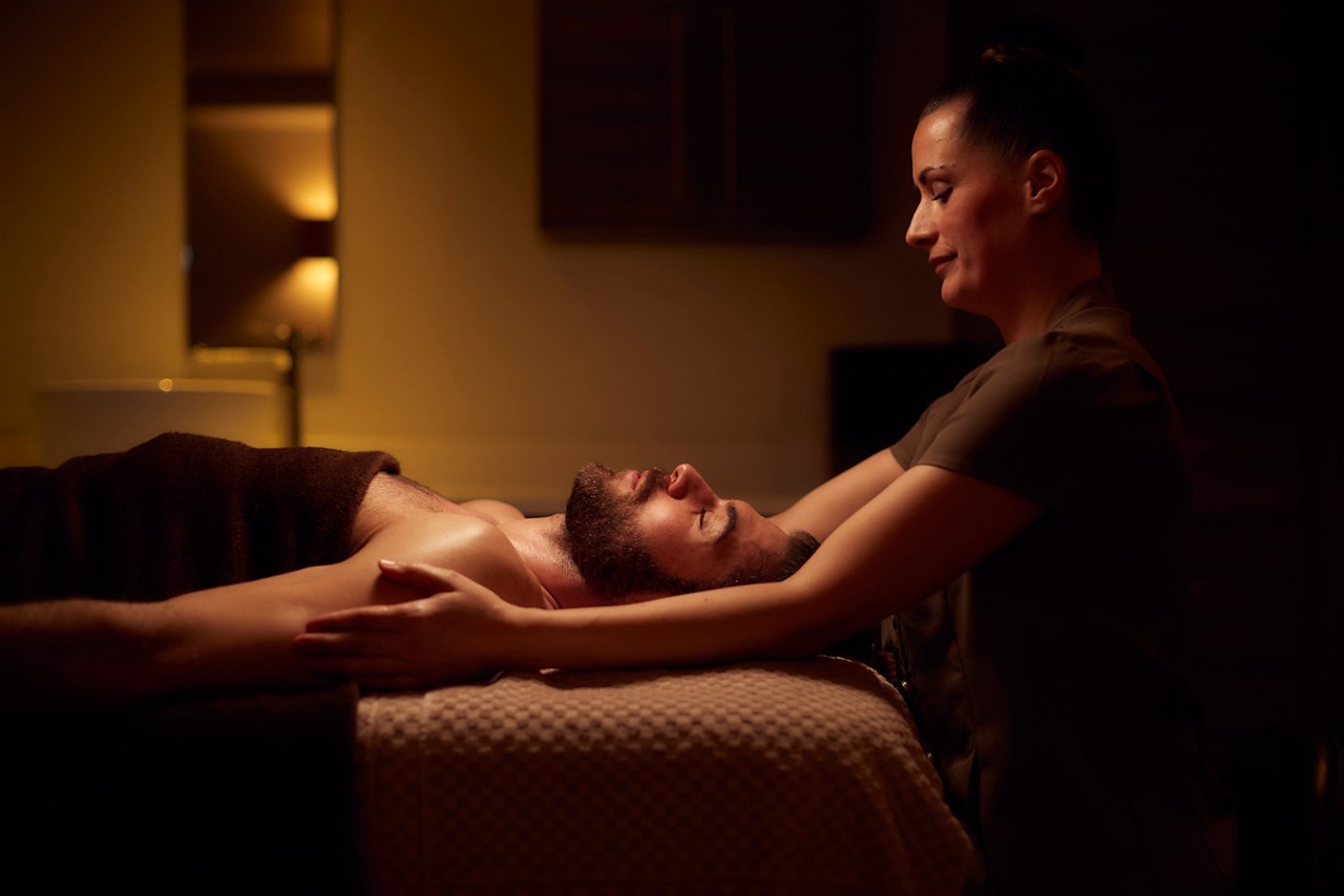 Spa therapist giving a man a relaxing body massage treatment.