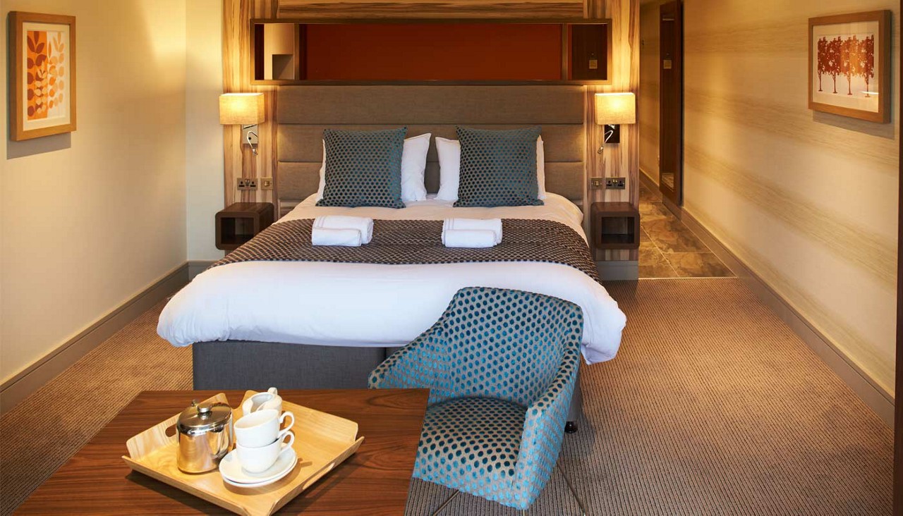 Double bed with bedside tables, lamps and rolled towels.