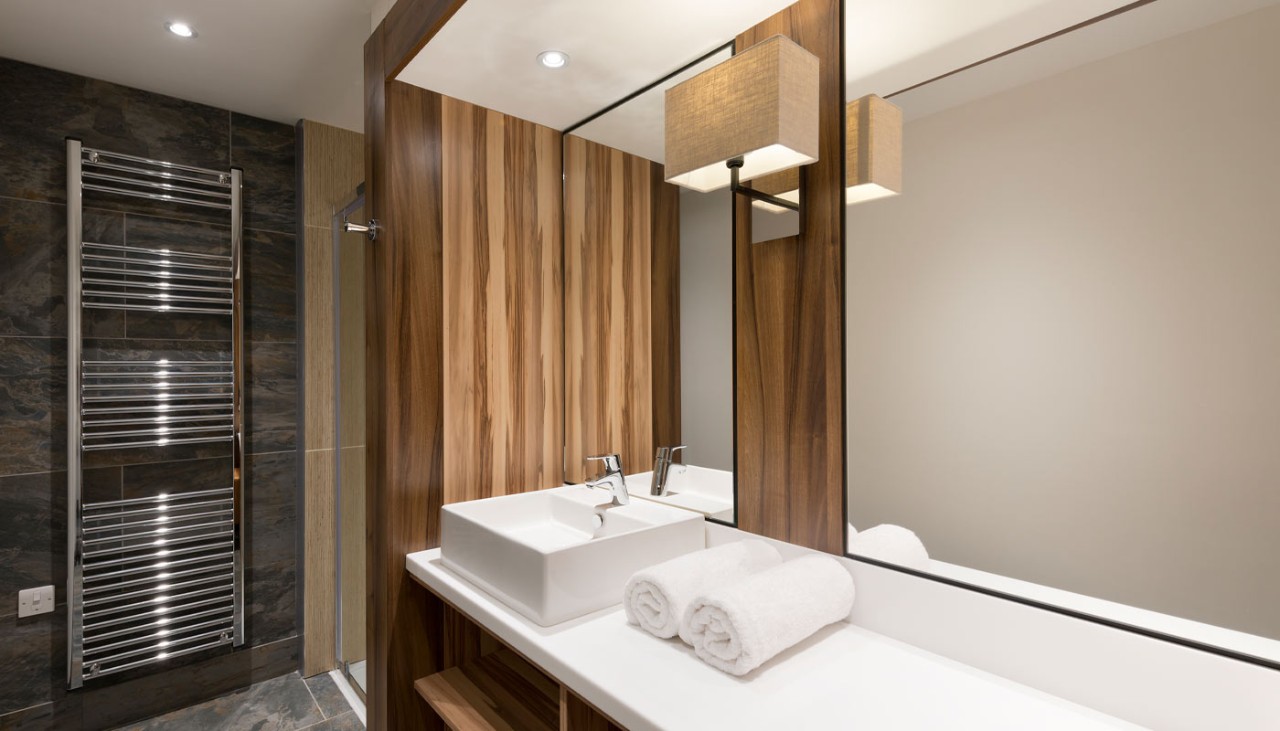 Bathroom with a large mirror, towels and a sink.