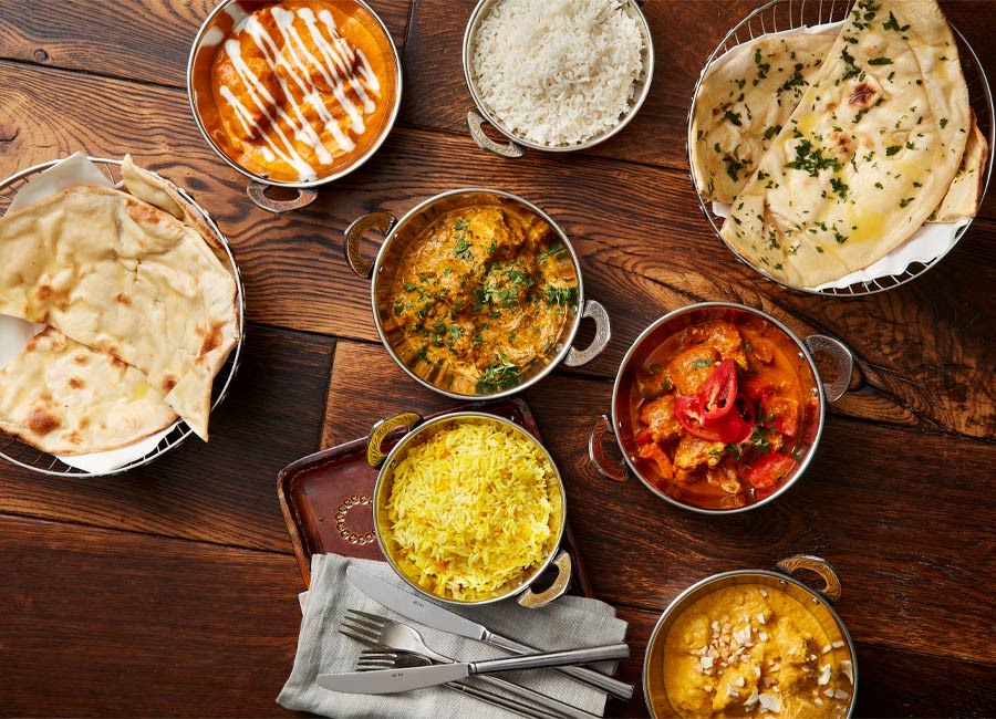 A selection of Indian dishes including, rice, naan bread and a variety of curries.