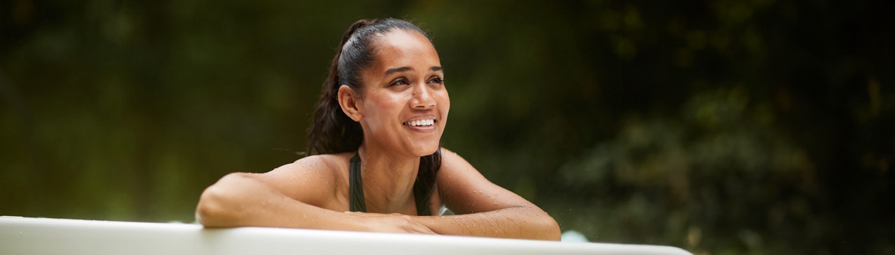 Woman leaning on the edge of an outdoor hot tub.