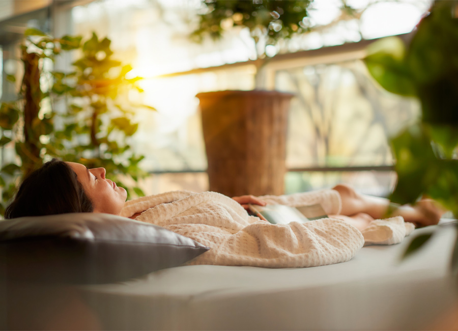 Woman laid on a Waterbed in a serene area with lots of plants and natural light.