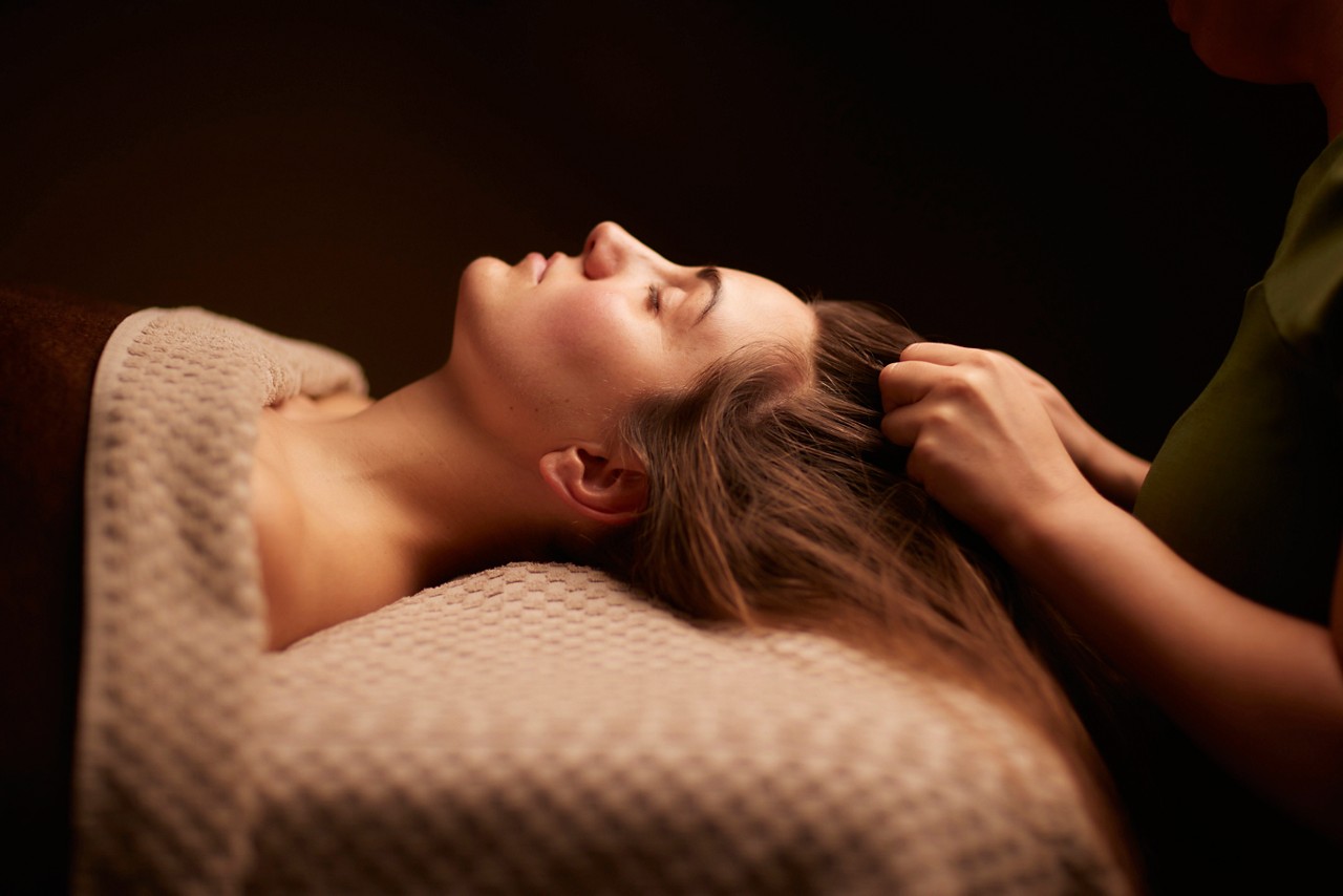 Spa therapist giving a woman a relaxing scalp massage.