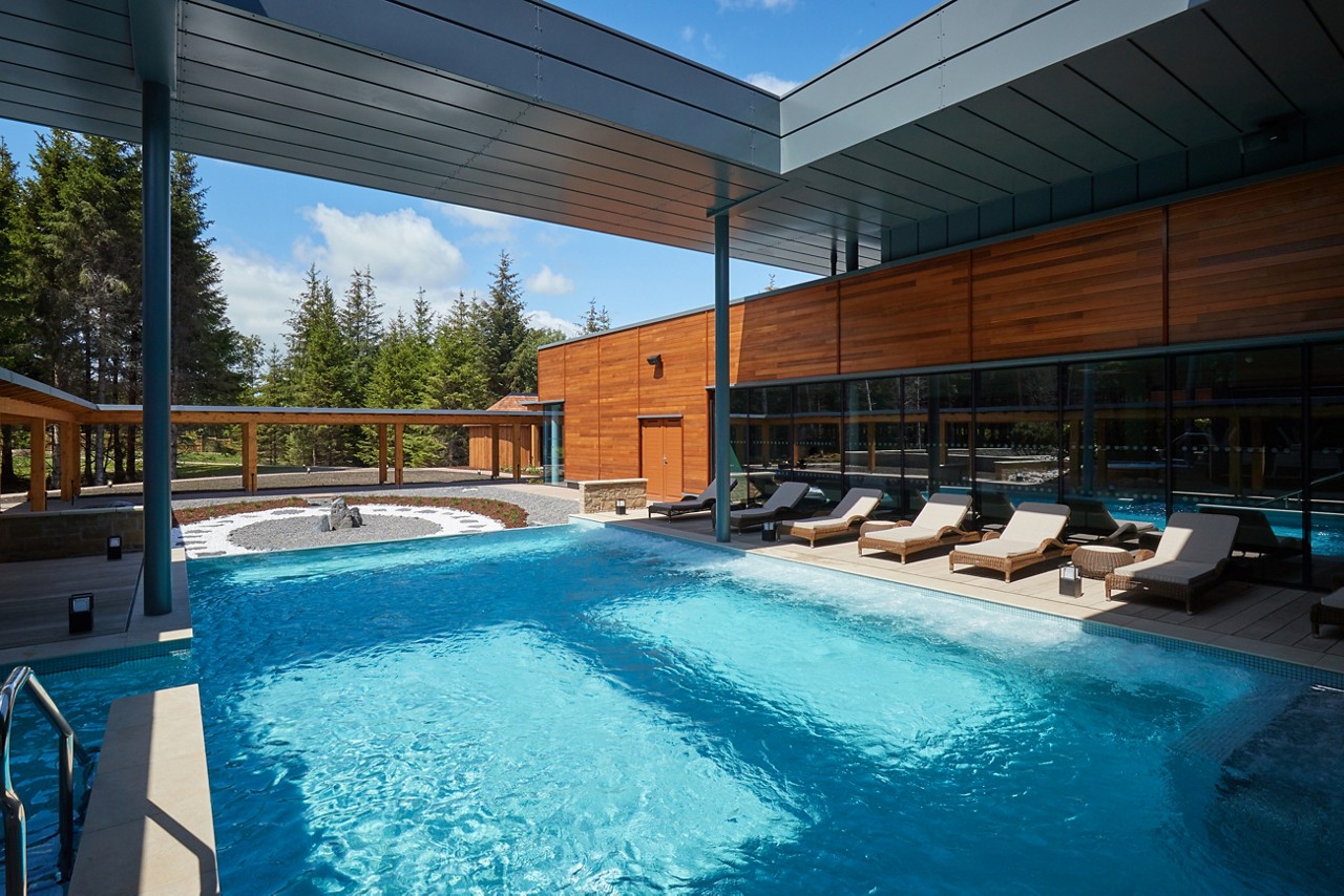 The sun reflecting on an Outdoor Pool surrounded by sun loungers.