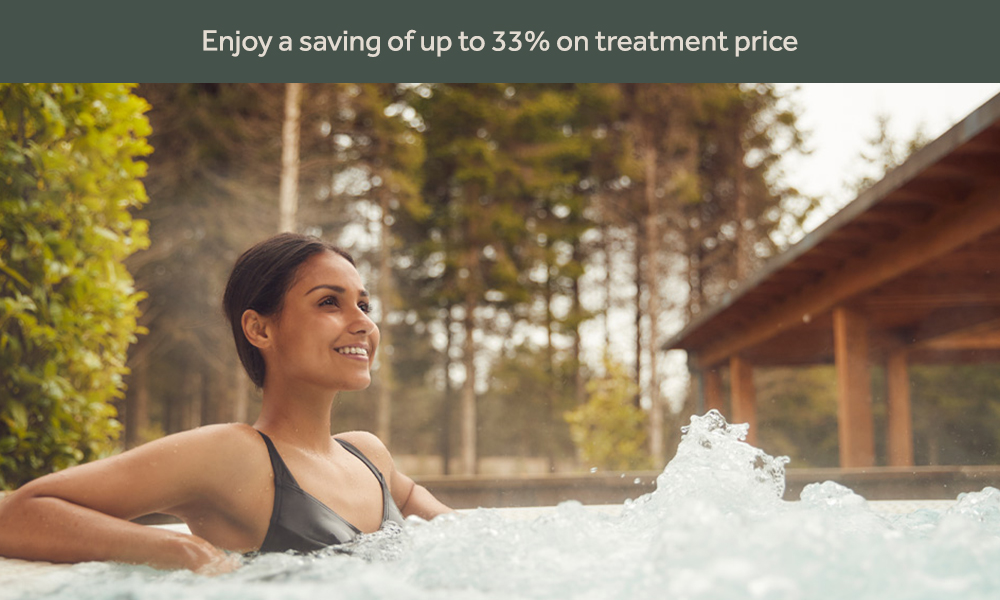 Woman soaking in a bubbling hot tub surrounded by the forest.