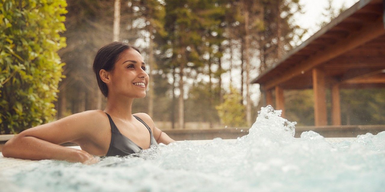 Woman soaking in a bubbling outdoor hot tub.