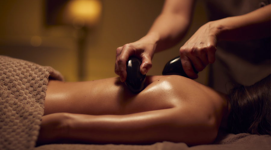 man receiving back massage using hot stones