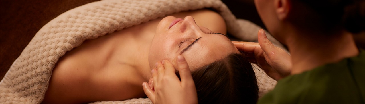 women laid on bed in towel receiving treatment