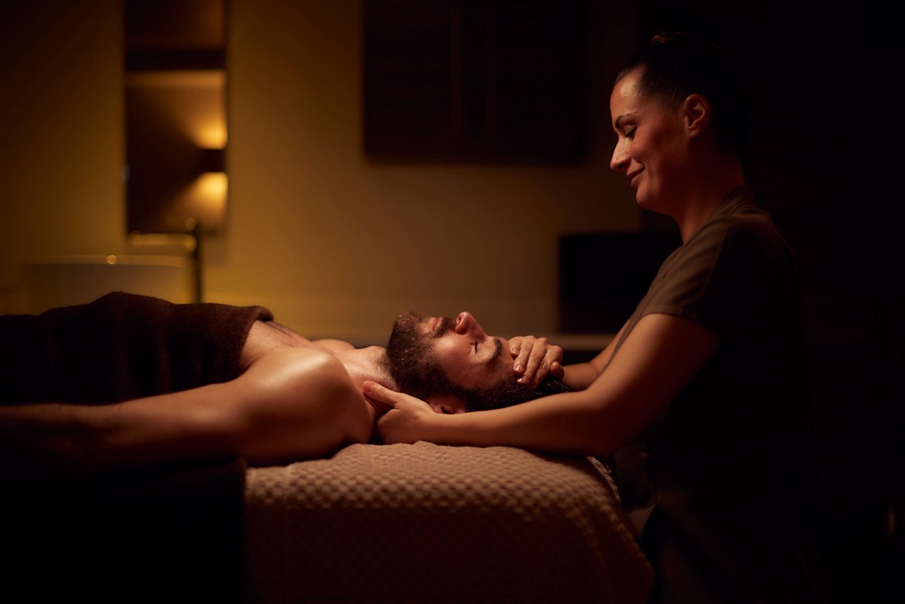 Spa therapist giving a man a relaxing massage treatment whilst lying on a spa bed