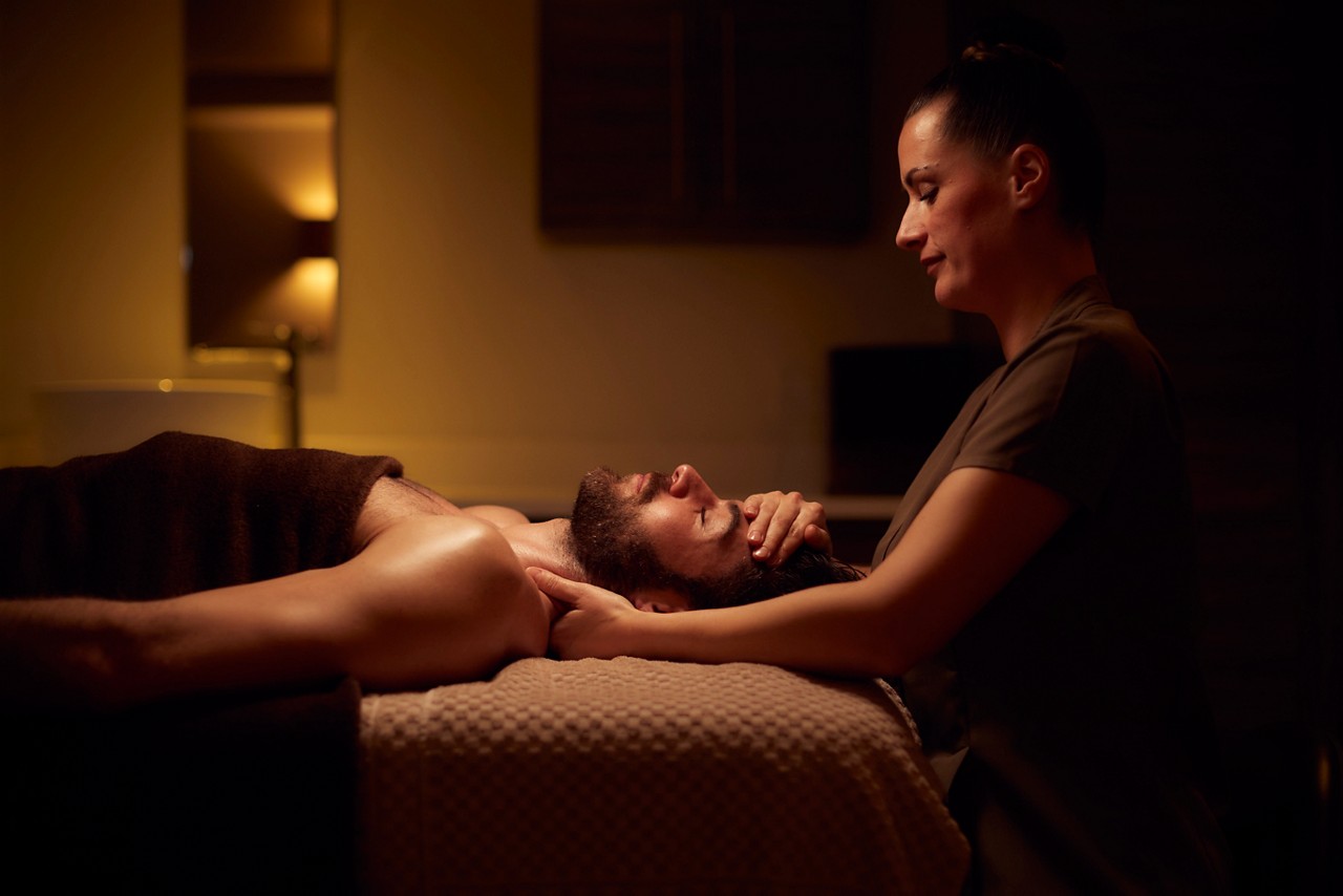 Spa therapist giving a man a relaxing massage treatment whilst lying on a spa bed