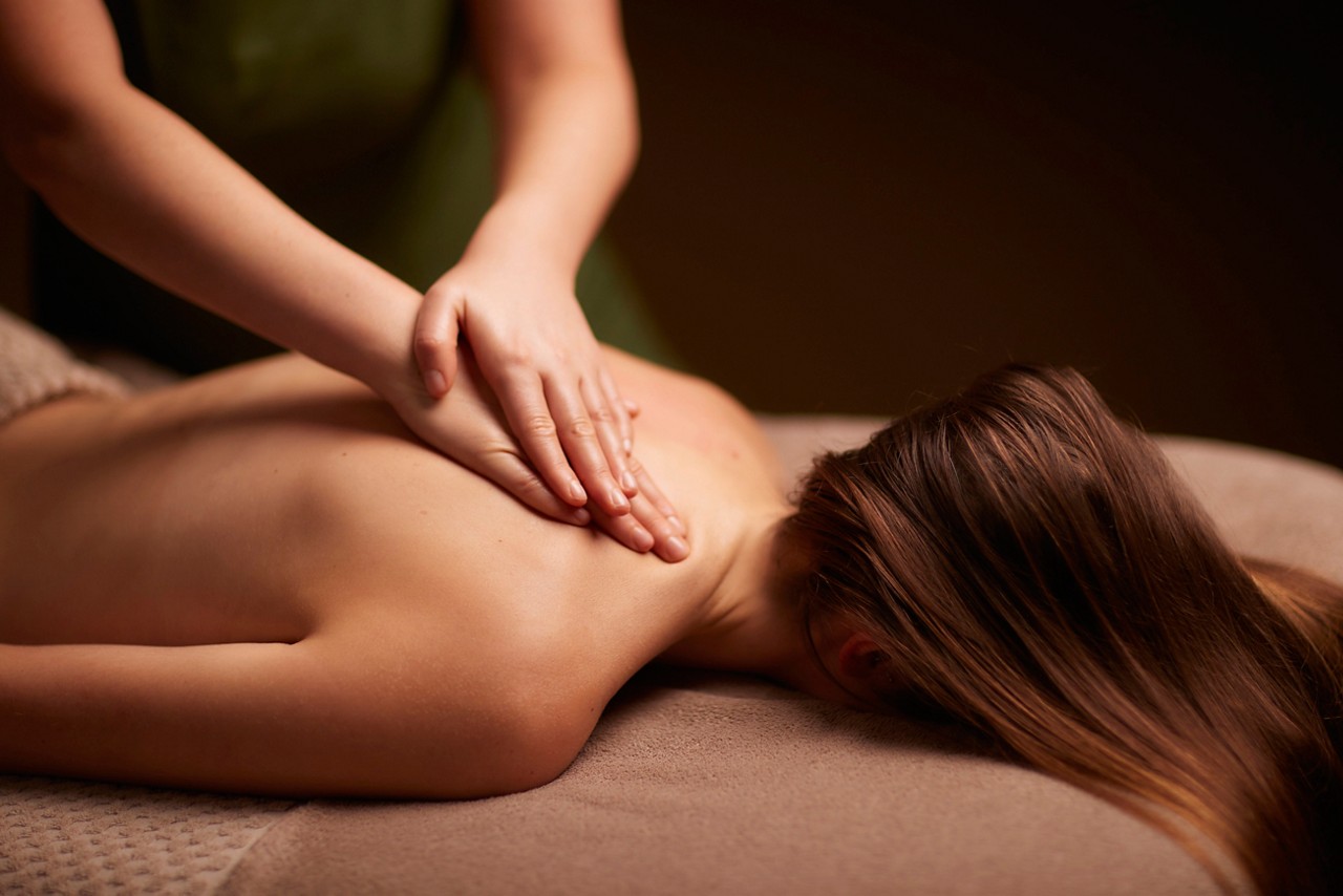 Spa therapist giving a woman a relaxing back massage body treatment.