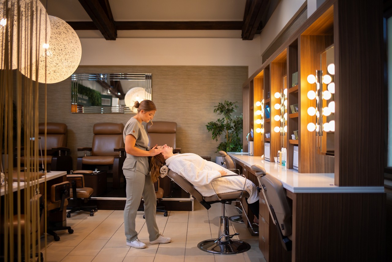 A therapist giving a facial treatment to a pregnant client reclining in a spa chair