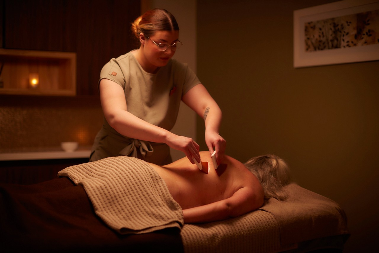 A massage therapist performing a comfort zone tranquility pro sleep wellbeing massage on a client lying on a treatment table