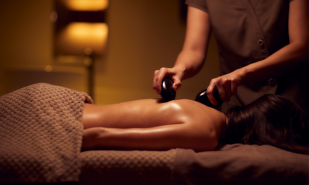 woman receiving back massage using stones