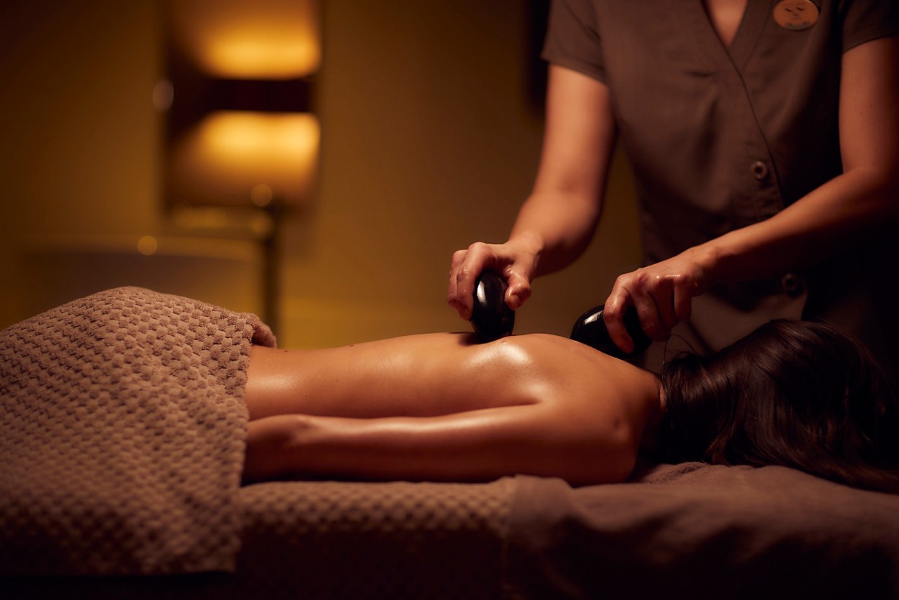 Spa therapist giving a woman a Thermabliss hot stone body massage.