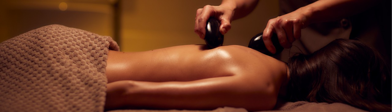 woman receiving back massage using stones 