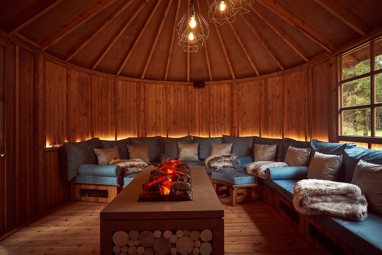 Scandinavian Snug with a central glowing fire and cosy seating.