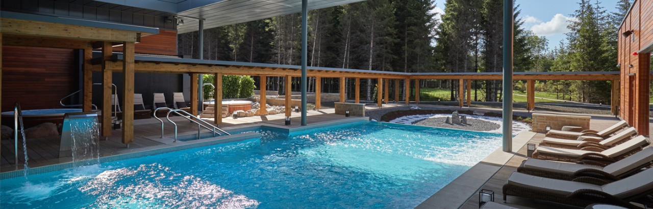 outdoor pool with view of forest and loungers on pool side