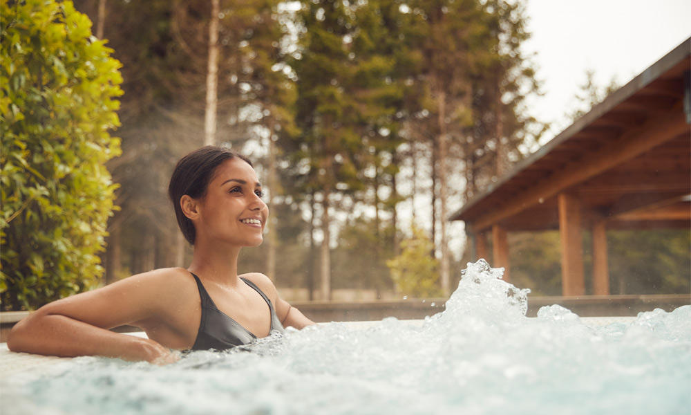 Woman in outdoor hot tub with forest behind her
