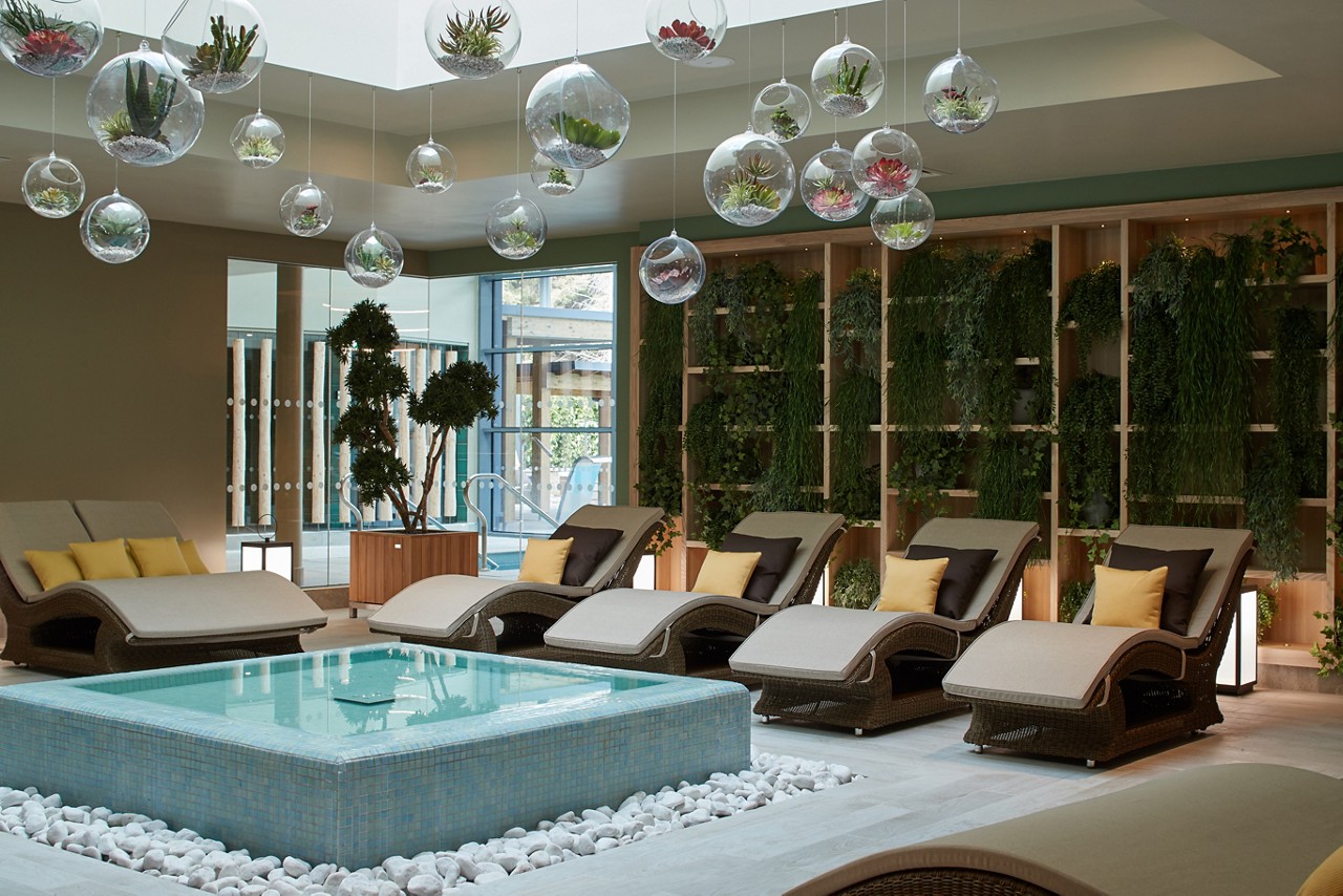 Cushioned lounging beds surrounding a tiled water feature inside the Forest Garden.