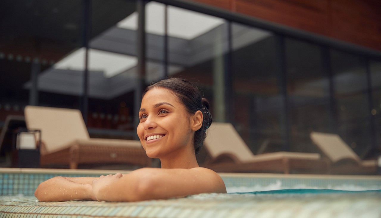 Woman leaning against the side of an outdoor pool.