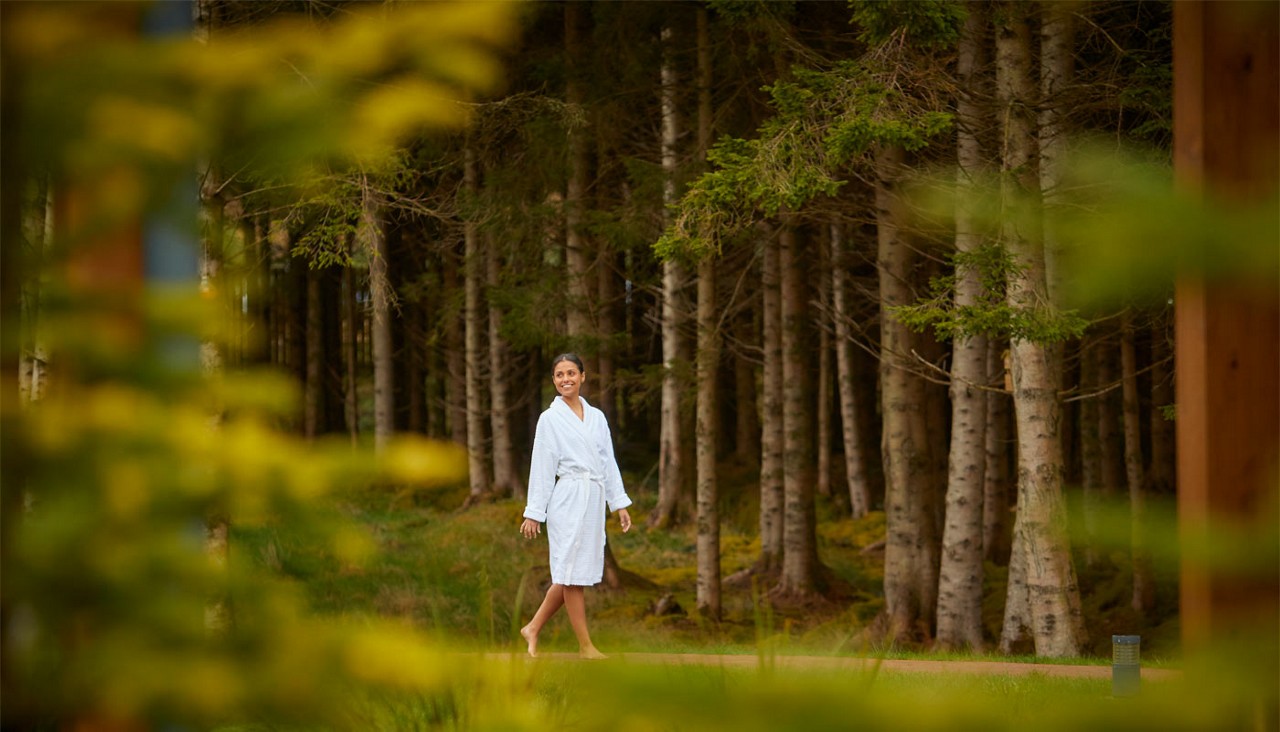 Woman walking along a path in the forest.