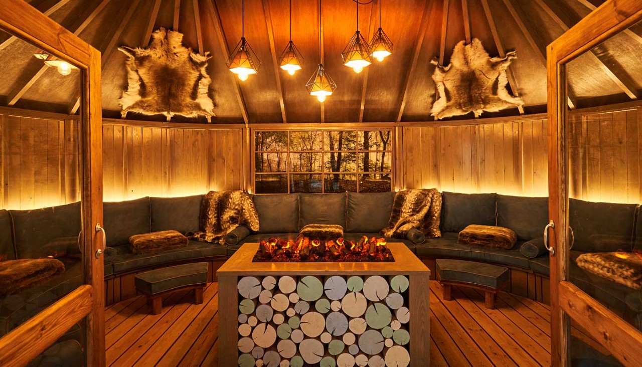 Inside a cosy Scandinavian Snug with hanging lighting, blankets and throw cushions.