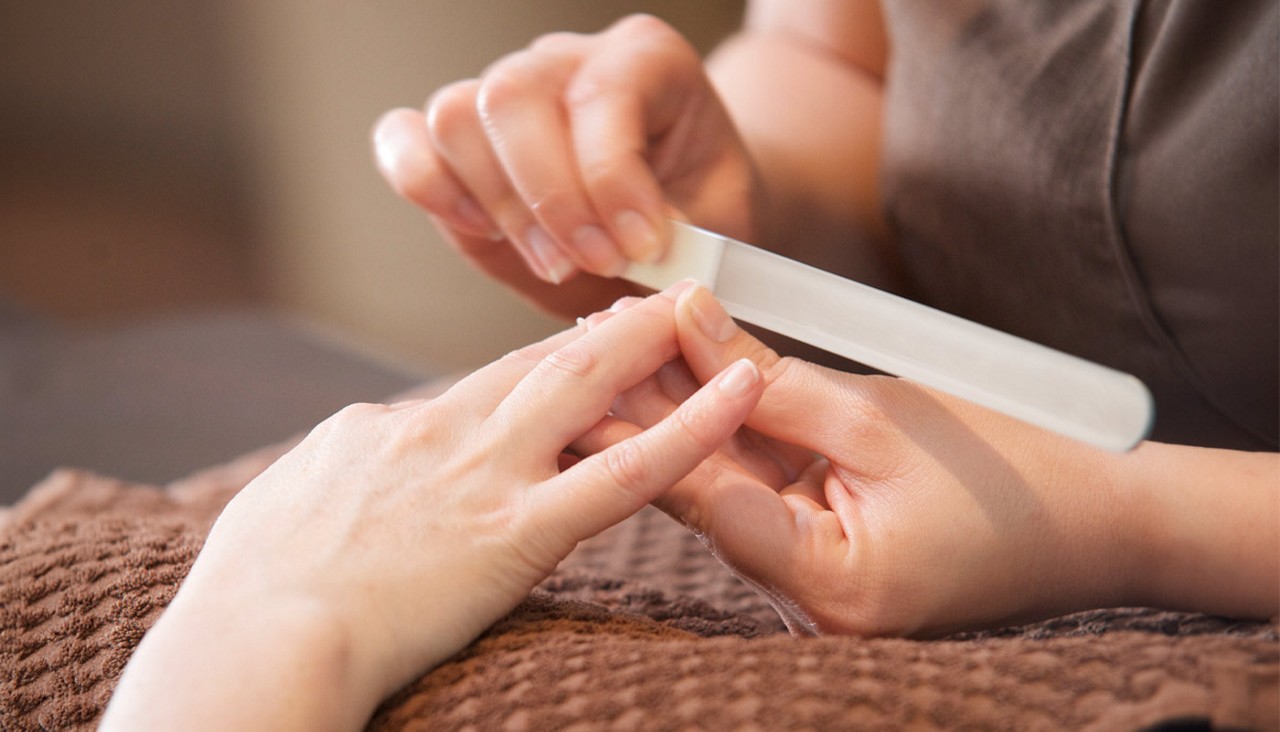 Woman having her finger nails filed.