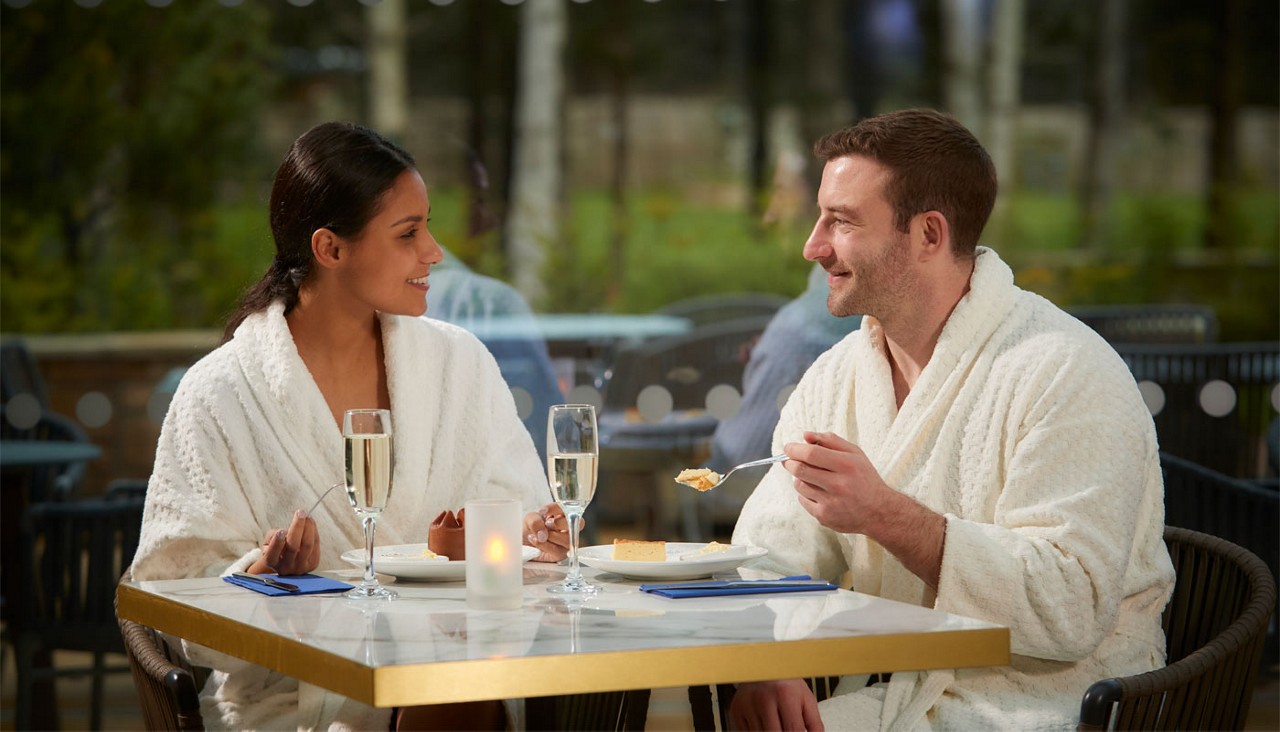 Couple sitting around a table, drinking champagne and eating sweet treats
