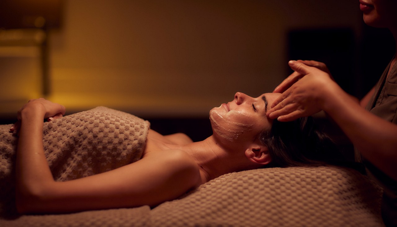 Woman laid on her back receiving a facial from a therapist.