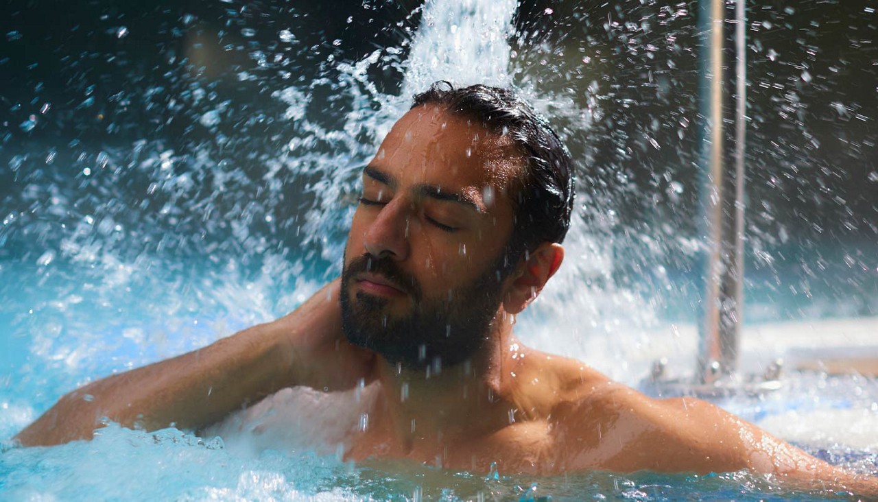 Man showering under a flowing water fountain.
