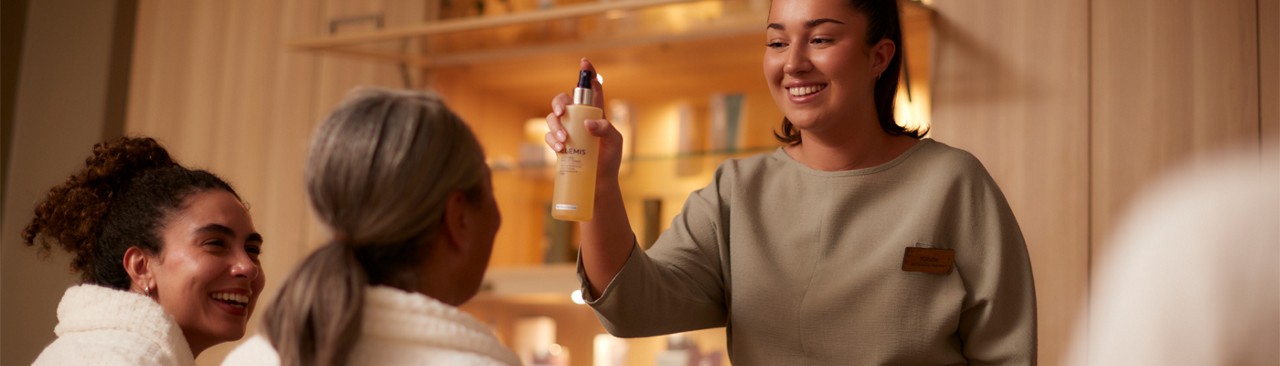 Spa therapist showing two ladies some products.
