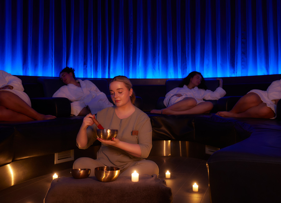Woman holding a metal bowl whilst people sleep on comfortable chairs. 